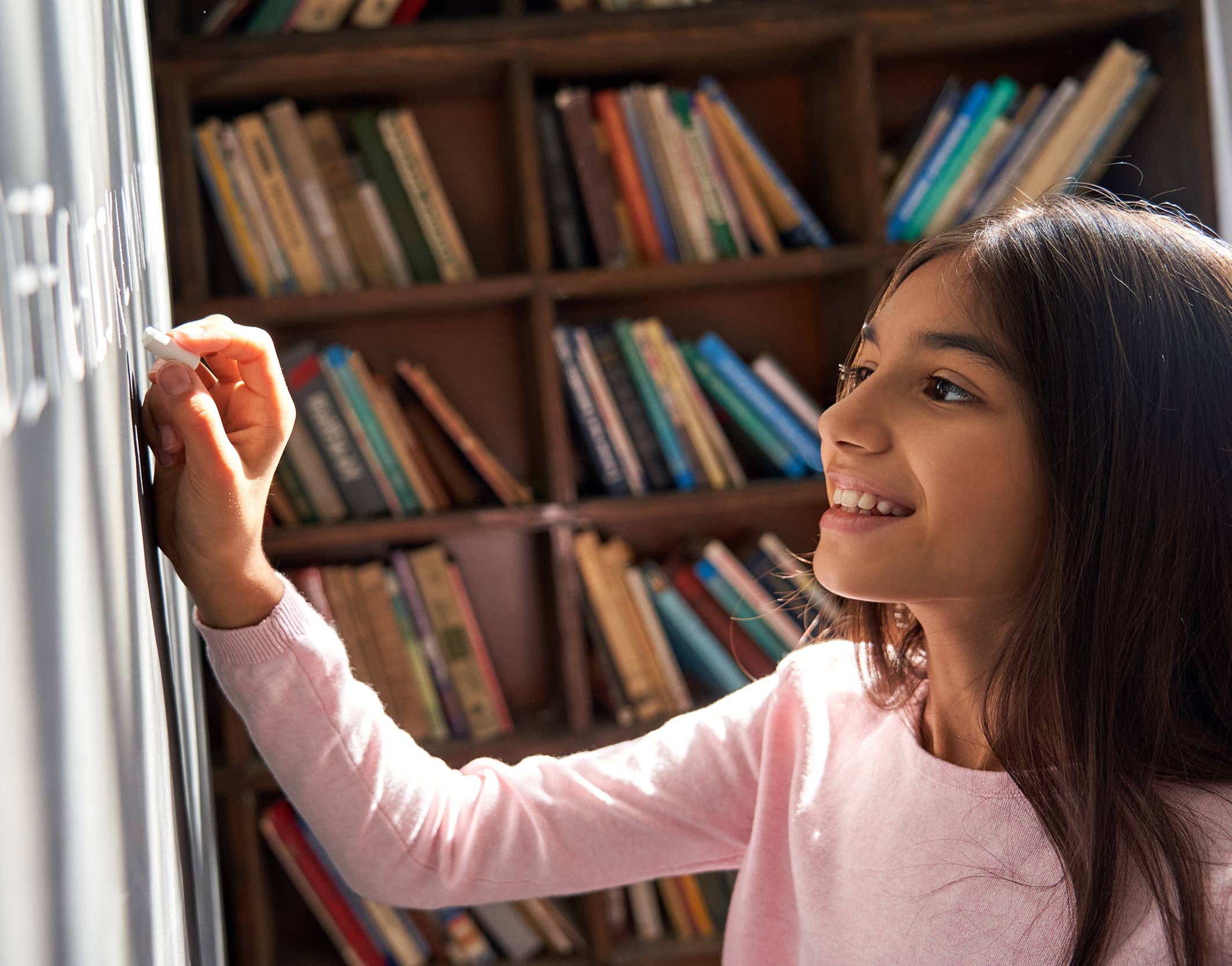 Young girl writing on chalkboard